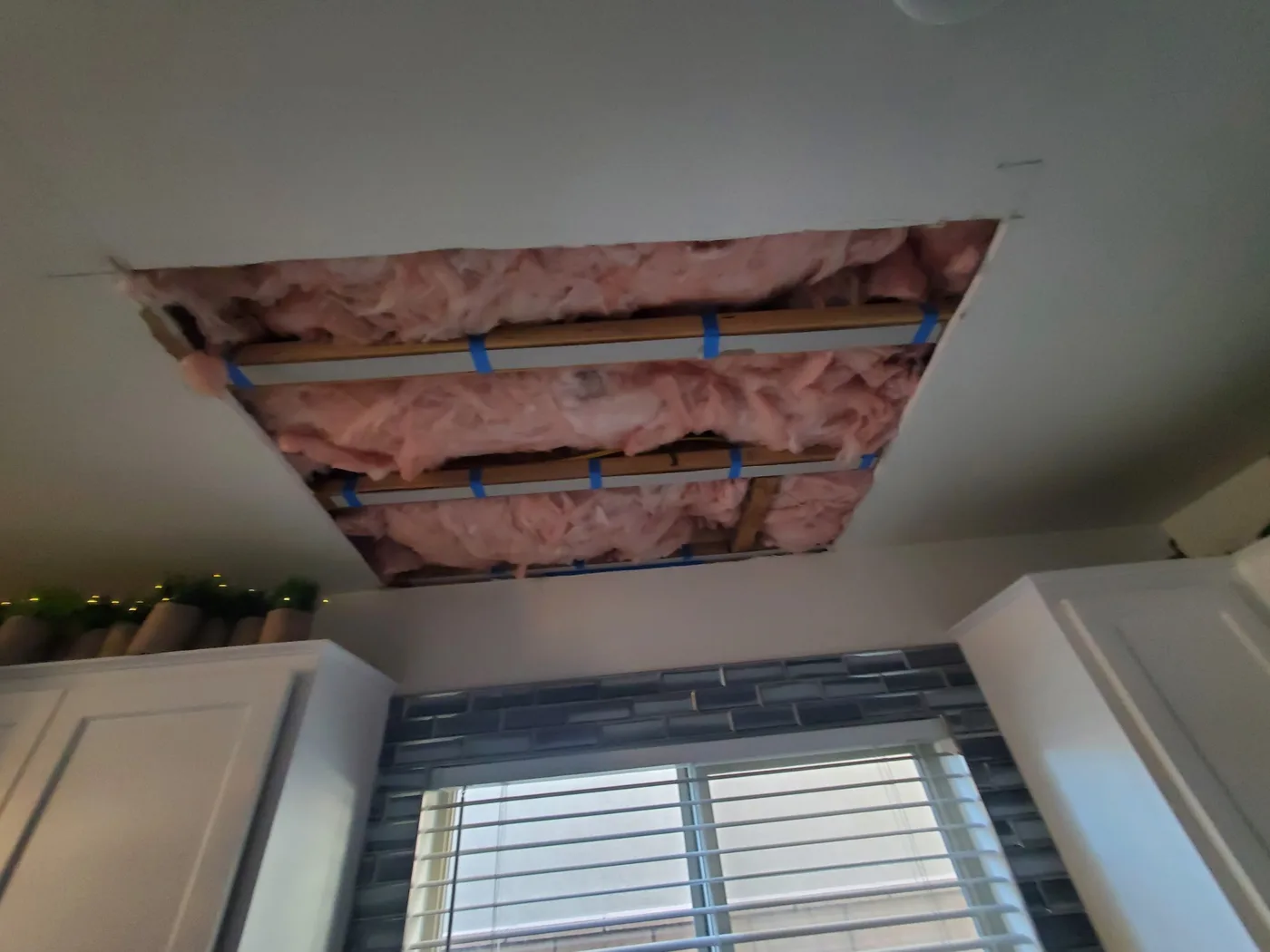 Before: Bathroom ceiling opened up with insulation and framing exposed