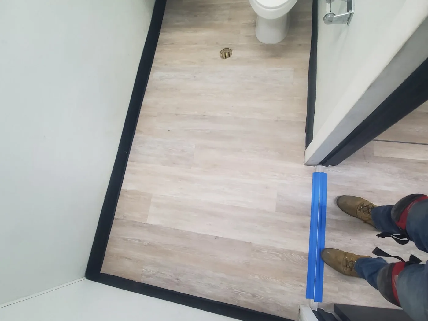 After: Same bathroom with new wood-look plank flooring and clean trim