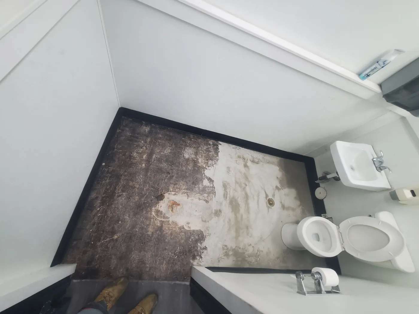 Before: Bathroom subfloor blackened by long-term water damage, fixtures removed