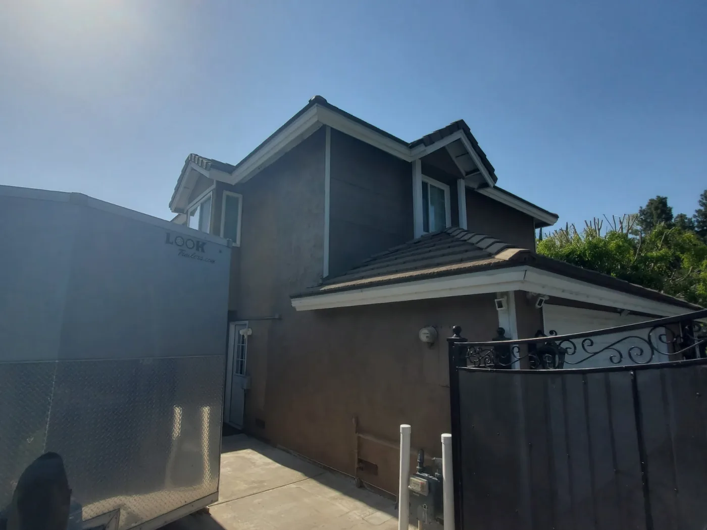 After: Same house exterior finished in smooth grey stucco with a new gate